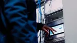 Factory worker in navy overalls touching a screen displaying manufacturing data