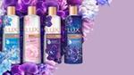 Four bottles of LUX bodywash on a bed of flowers. The bed of flowers is resting on a lavender background.