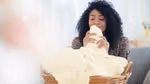 A person pulling a blanket from a basket close to their nose and smelling it.