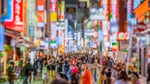 An Asian street scene at night with people walking between lit up signs.