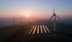 Aerial view of rural landscape showing wind turbine and solar panels in field.