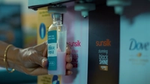 A refill station with Unilever brands including Sunsilk and Dove. The image shows a bottle being filled with pink Sunsilk product and a person holding the bottle.