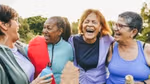 Four women laughing together outdoors.