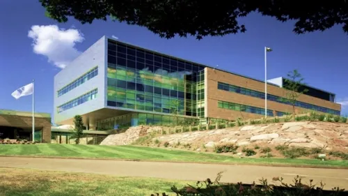 The exterior of an office building built on a hill. One section is mainly glass with a grey wall, while the rest is red brick. There is a flag on a pole displaying the Unilever logo.