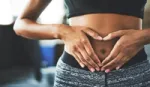 Woman making a heart shape with her hands over her stomach