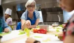 Woman in blue apron leaning over a kitchen counter