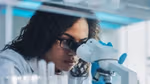 Woman looking through a microscope in a lab