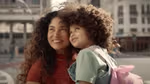 A shot of a woman holding a little girl from Dove’s film ‘The Code’. They have curly brown hair and are looking up, smiling.