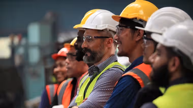 Smiling workers in hard hats and high-visibility clothing