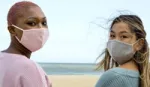 Two people wearing facemasks, one pink and one wearing grey.