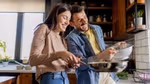 Couple smiling and cooking together in a kitchen.