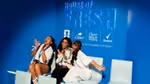 Three women smile for a photo at Unilever's House of Fresh. Dove, Dove Men+Care and Rexona logos are on the wall behind them.