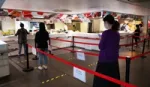 Employees line up in the office canteen, social distancing using markings on the floor