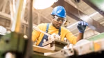 Man wearing hard hat and safety glasses working at a machine in a workshop