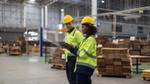 Man and woman in hard hats having a conversation in a warehouse